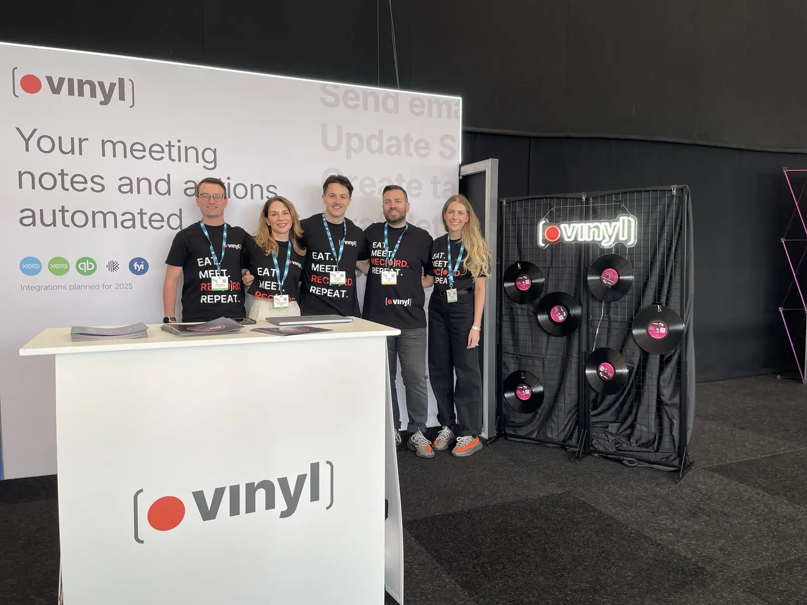 The Vinyl team on their stand at the Digital Accountancy Show London, in Eat Meet Record Repeat t-shirts beside a wall of vinyl records